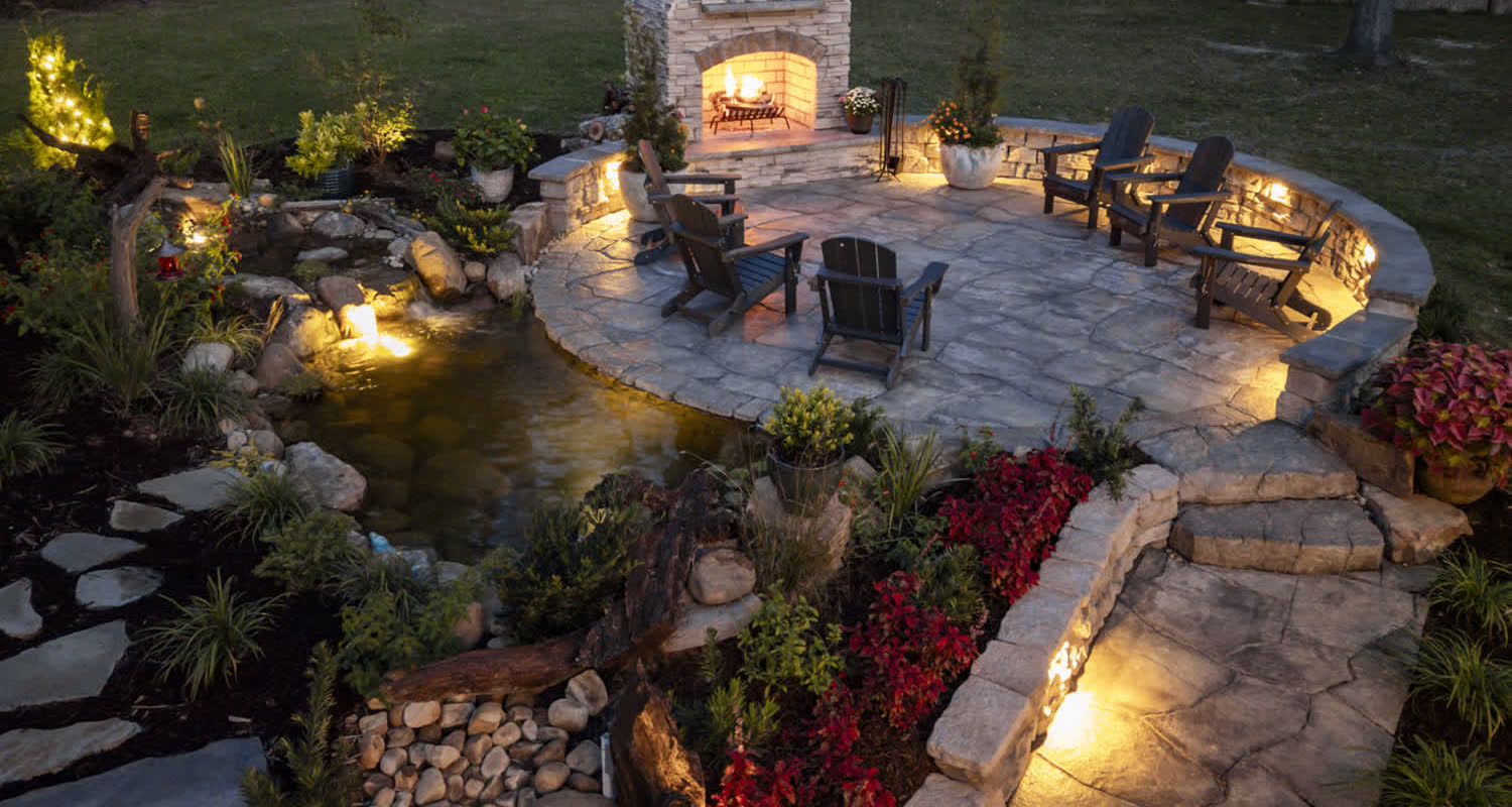 A Superscapes backyard retreat at dusk — water feature, fire, and seating